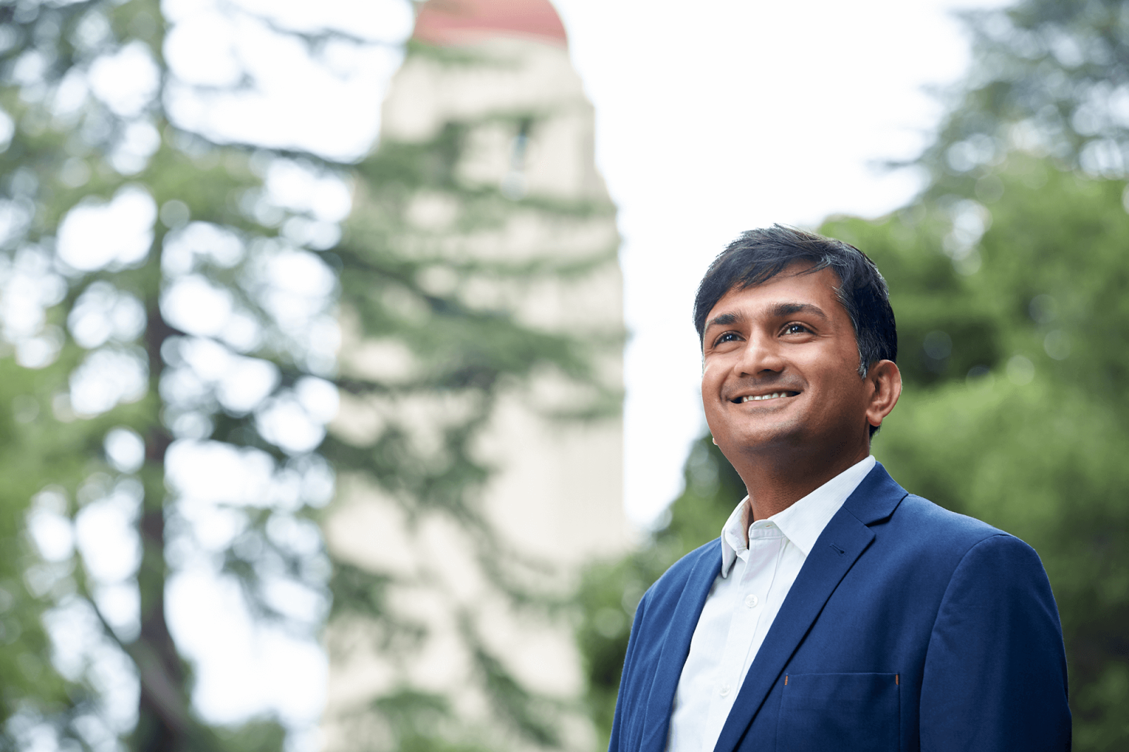 Man in suit smiling, Hoover tower in background. 