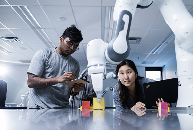 Two students working on a robotic arm