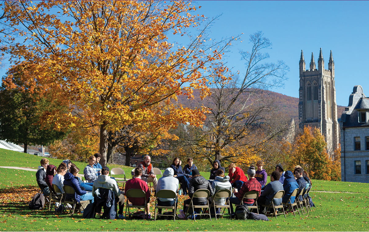 photo of students having class outside under an autumn tree