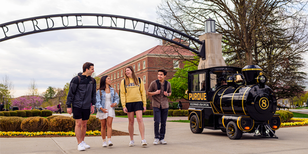 Students walk under the Gateway to the Future Arch alongside the Boilermaker Special