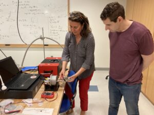 Daniella Buna and a student work on some equipment in an engineering physics lab.